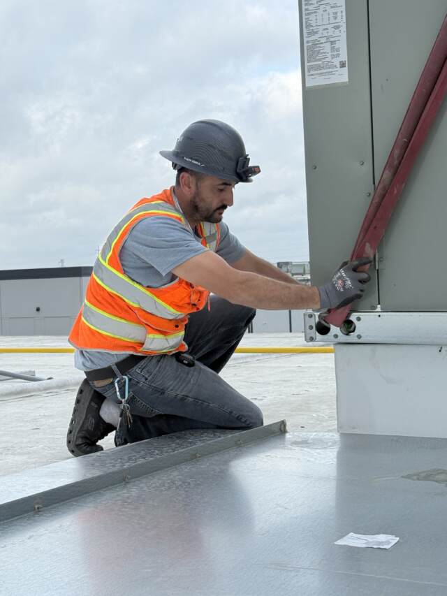 HVAC technician performing TAB services on rooftop unit — Sysgration Plano facility